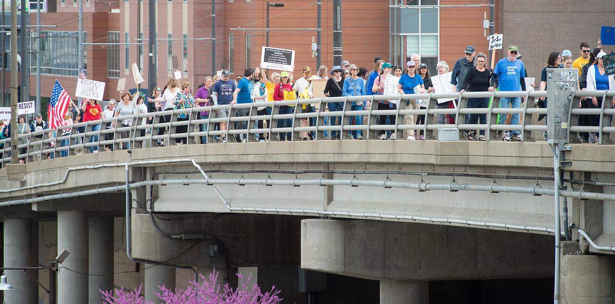 Demonstrators hold signs while they walk south along Main Street during a pro-democracy march that took aim at the Trump administration’s policies Saturday, March 29, 2025 in downtown Kansas City.