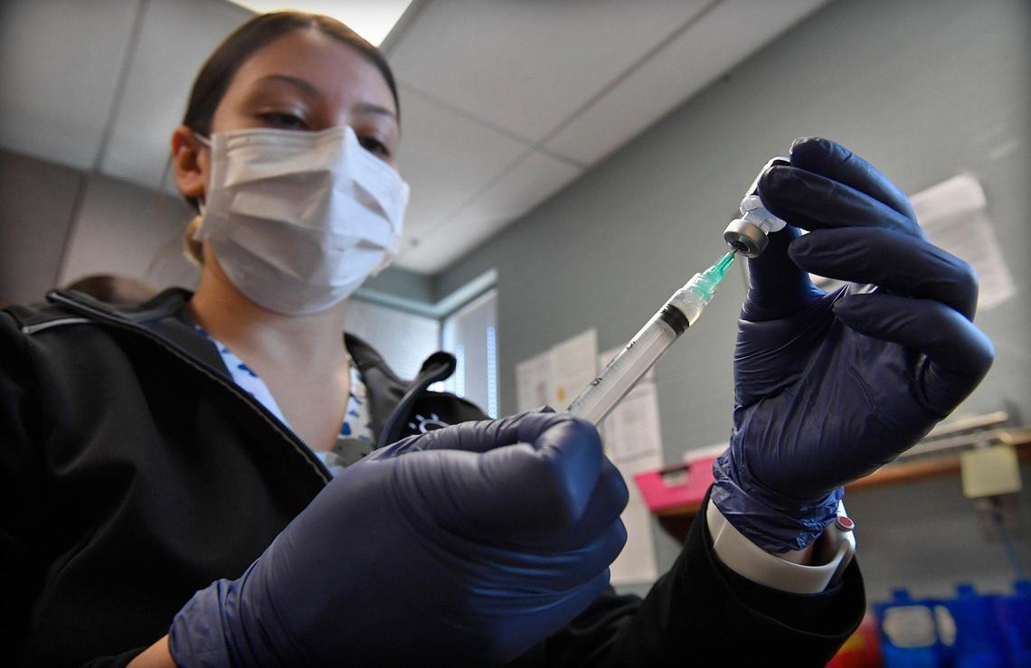 Breana Slusser, a medical assistant at Family Health Care KC, prepares a COVID-19 booster shot for a patient on Tuesday, Dec. 21, 2021, at the clinic in Kansas City, Kansas.