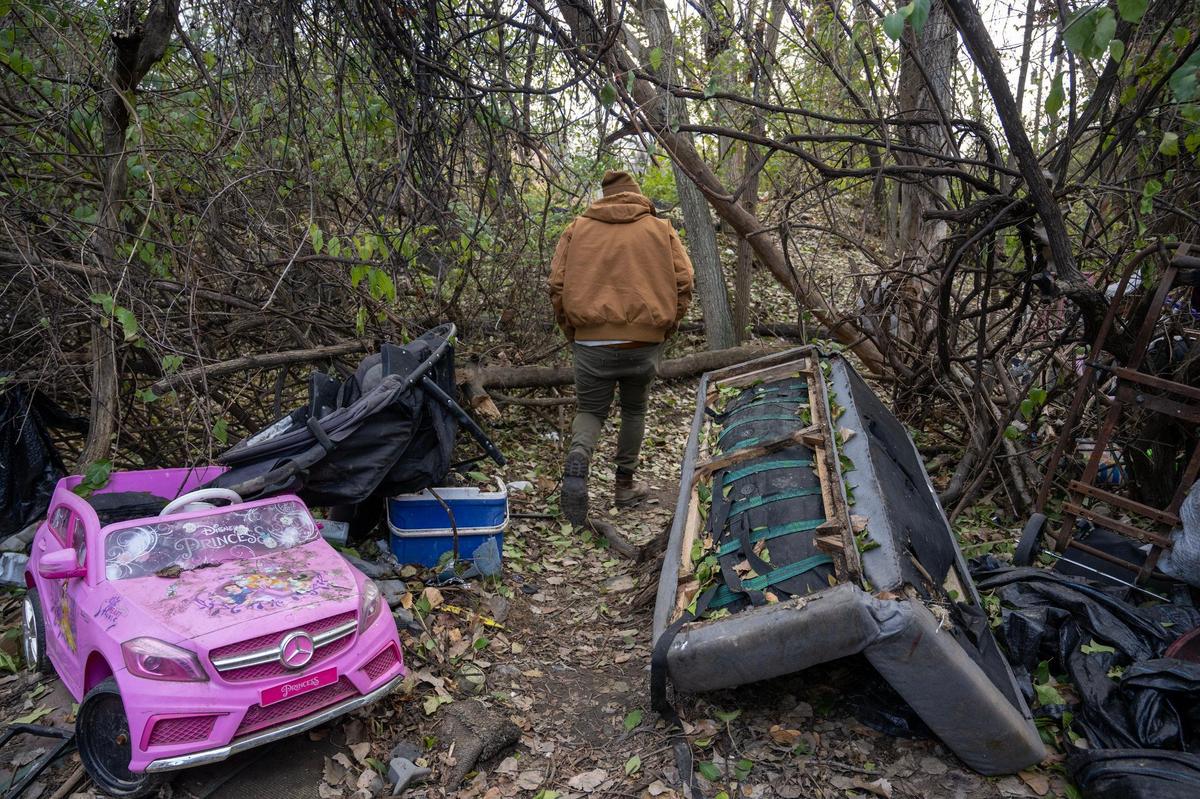 A city outreach worker walks a path between homeless camps among the trees in northeast Kansas City.