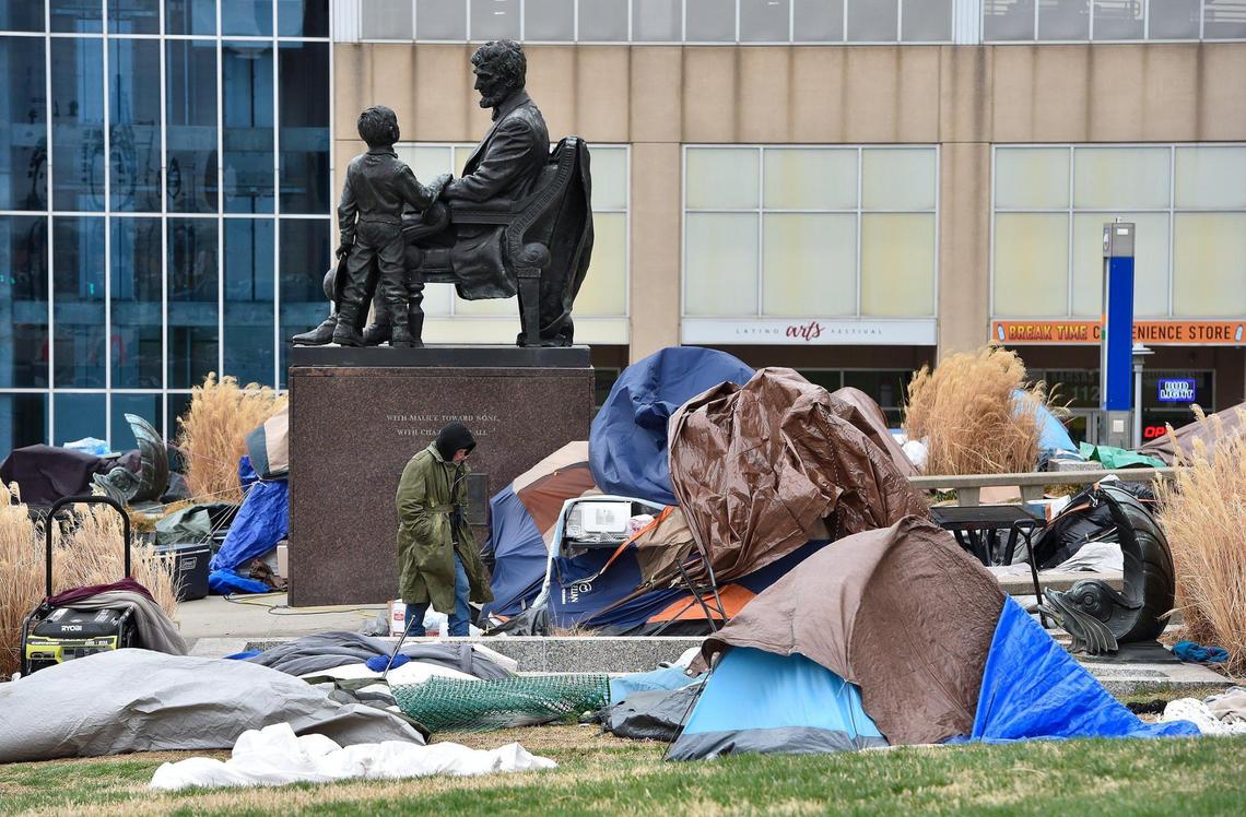 Homeless people set up a tent camp in front of City Hall in Kansas City in early February. On Thursday, strong overnight winds had tossed belongings over the area. One homeless resident, pictured walking, said the winds damaged his tent and he was wondering how to get a new one.