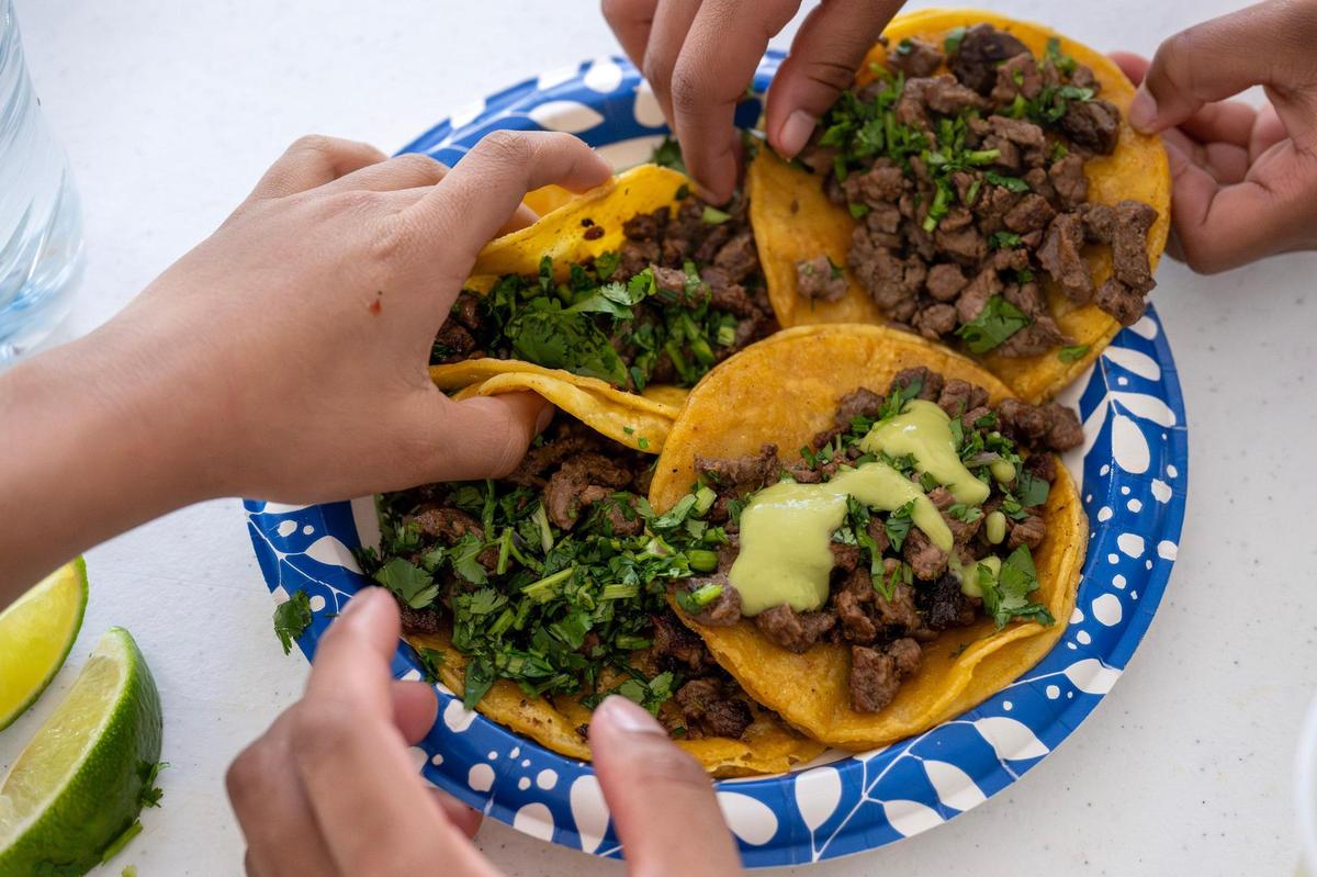 Visitors grab carne asada tacos from a plate during the Cinco de Mayo Festival at the Guadalupe Center in 2025, in Kansas City. The annual celebration features traditional Mexican music, dance, food and community festivities.