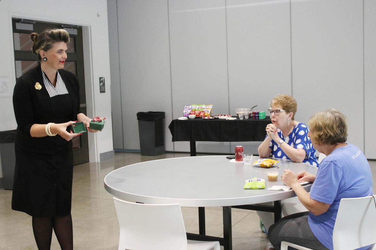 Yvonne Svenson shows Brenda Barrand of Overland Park and Sally Looney of Lenexa an ash tray set that someone might give as a wedding gift in the 1940s and 50s during an event for the Johnson County Museum’s new post-war wedding exhibit.