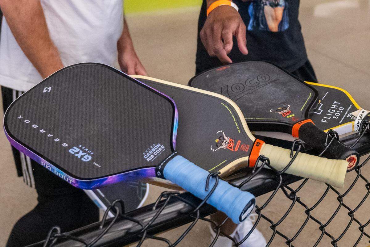 Pickleball paddles are stuck in the fence to reserve the court at a meeting of the Black Pickleball Club at SW19 at the Stadium, on Sunday, February 22, 2026, in Kansas City. The sharing of courts is very informal with paddles acting as a placeholder for the next team on the court.