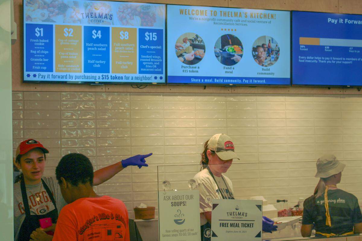 Volunteers assist a customer at Thelma’s Kitchen on Monday, June 16.