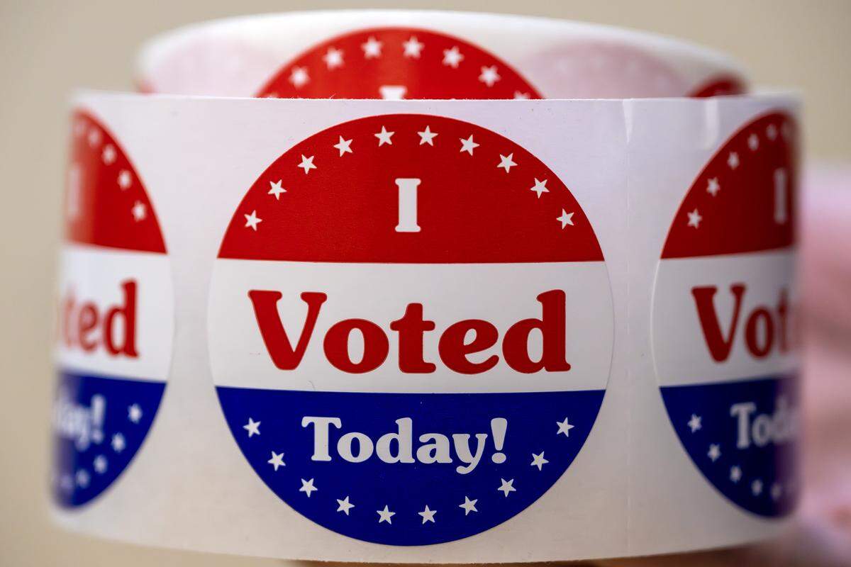 “I Voted” stickers are held up by a volunteer at Van Horn High School during Election Day on Tuesday, April 7, 2026, in Independence.