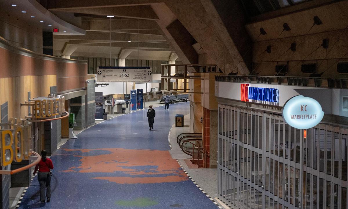 A few travelers and airline workers walk through the terminal B hallway on the last day of operation at Kansas City International Airport’s old terminals on Monday, Feb. 27, 2023, in Kansas City.
