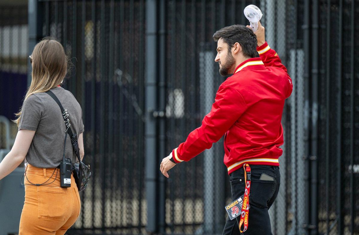 Tyler Hynes, star of “Holiday Touchdown: A Chiefs Love Story,” cooled down with a fan while wearing winter Chiefs gear like everyone else in the movie filming this week at GEHA Field at Arrowhead Stadium.