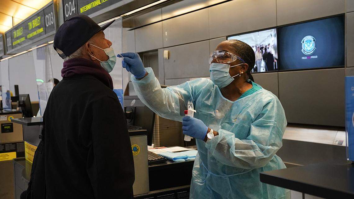 Licensed vocational nurse Caren Williams, left, collects a nasal swab sample from a traveler at a COVID-19 testing site at the Los Angeles International Airport in Los Angeles, Monday, Nov. 23, 2020.