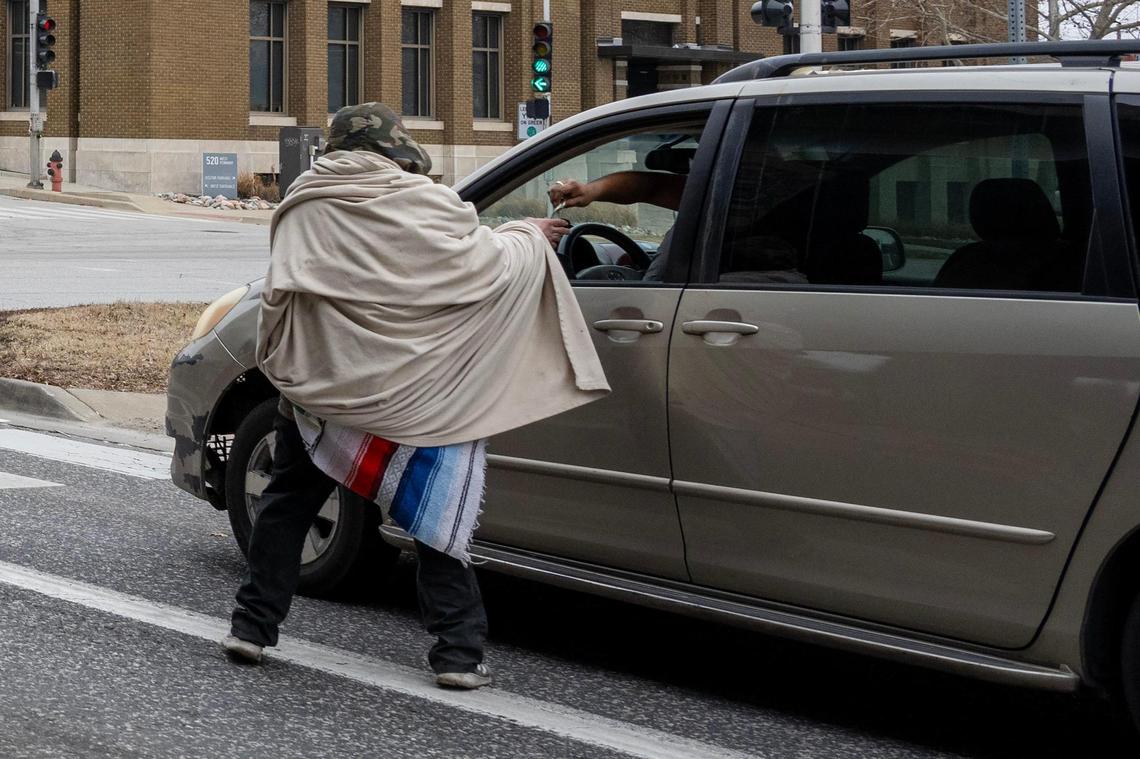 A driver hands money to a Thomas Gonzalez, 38 and houseless, in an area where panhandlers are often found along West Pennway Street. 