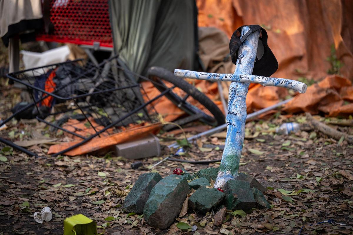 A wooden cross memorializes Marcia Boring, 52, and Eugene Shaw, 50, both of whom were killed in May 2022 at a homeless encampment north of Kansas City’s Columbus Park neighborhood.