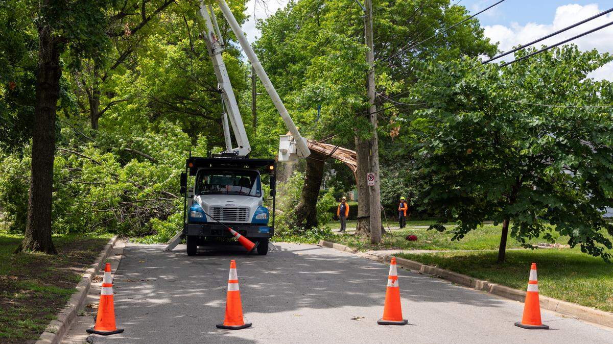 A crew works to clear a fallen tree across Main Street near its intersection with East 80th Street in Kansas City’s Waldo neighborhood on Wednesday, June 26.