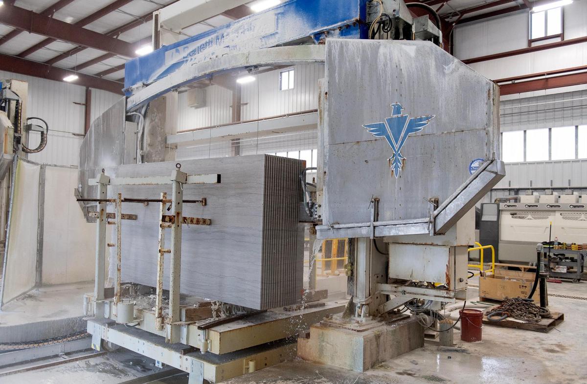 A machine at the Phenix Marble Co. cuts slabs out of a block of limestone.