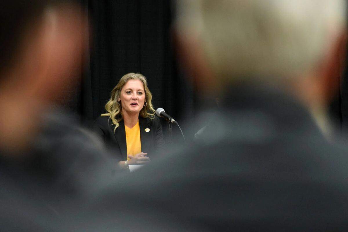 Peering through the crowd of Mizzou Athletics staff, fans and supporters, new women’s basketball coach Kellie Harper answers questions during her introductory news conference on Monday, March 31, 2025, inside the Mizzou Arena practice gym. Harper is the fifth coach in program history.
