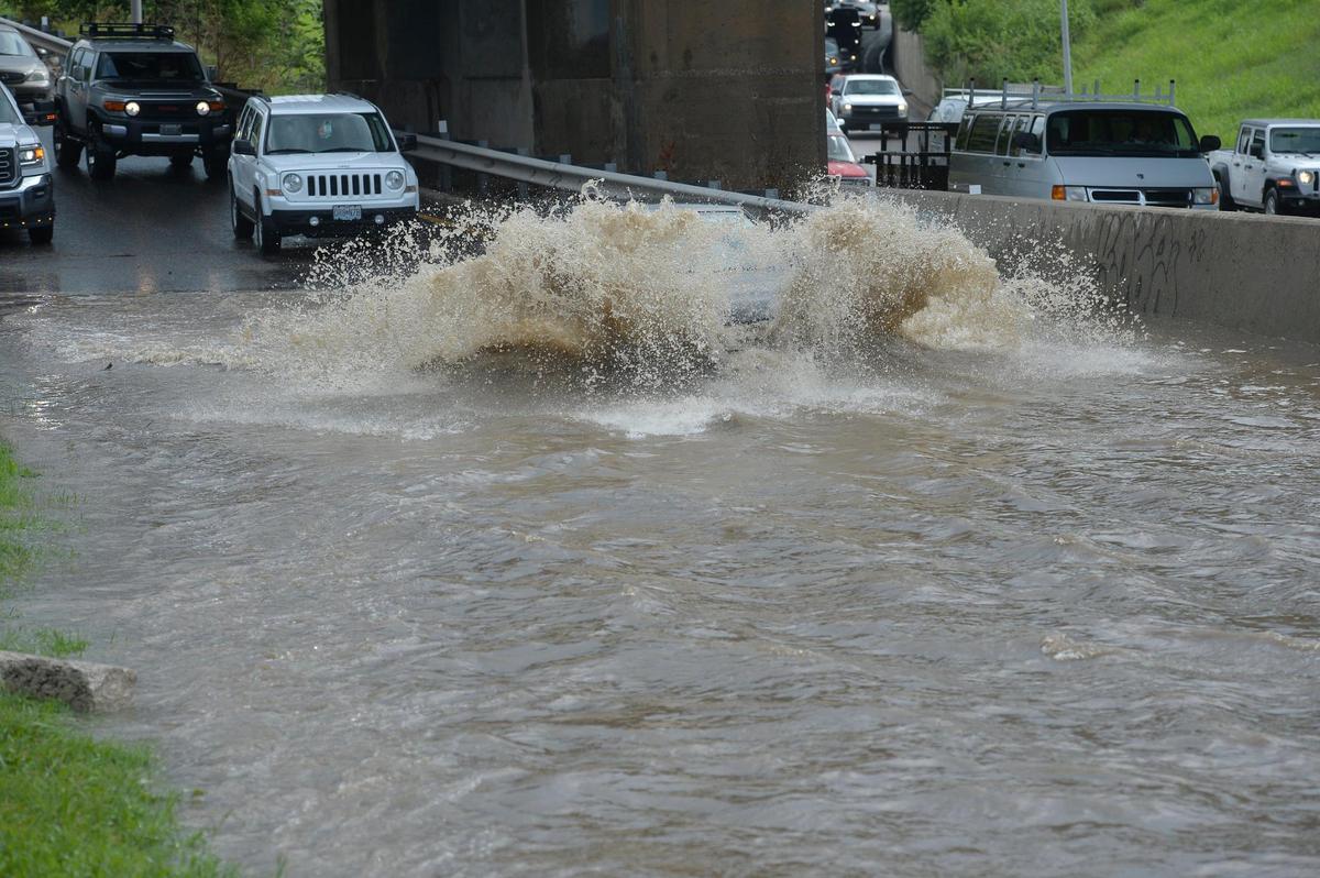 Cars splash through floodwater on the Southwest Trafficway on ramp to northbound Interstate 35 heading toward downtown Kansas City, Wednesday after heavy rains flooded the area. The interstate was impassible for a while due to water pooling in the lanes.