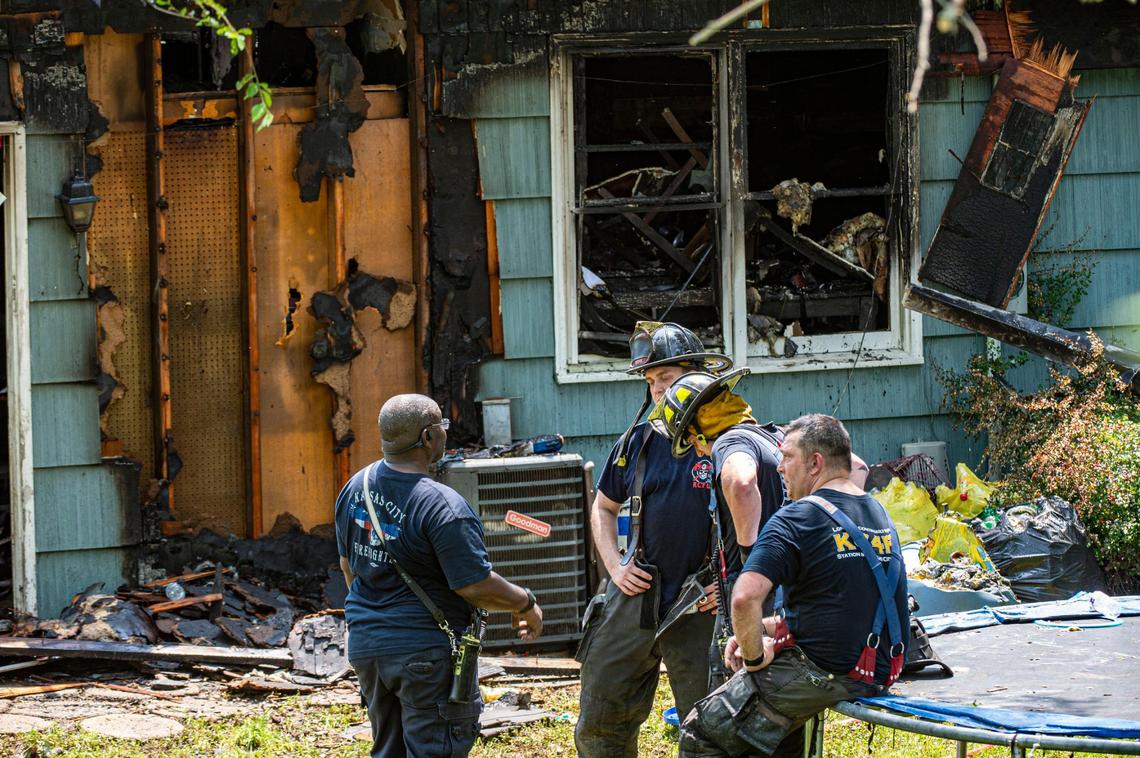 Kansas City Fire Department firefighters talk in the backyard of the house 7212 N. Avalon St. after battling a blaze there Wednesday that sent four people to the hospital including three children.