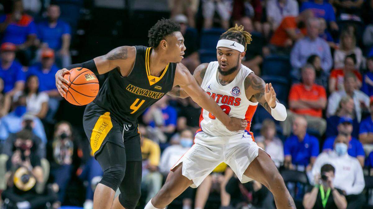 Milwaukee guard DeAndre Gholston (4) looks to pass with pressure from Florida guard Brandon McKissic (23) during second half action of an NCAA college basketball game Thursday, Nov. 18, 2021, in Gainesville, Fla. (AP Photo/Alan Youngblood)