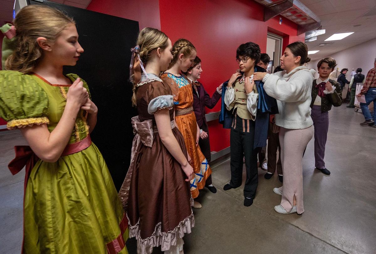 Children in the cast of “The Nutcracker” wait in a hallway backstage before being guided by “kid wranglers” to the stage for the dress rehearsal. Araceli Shaw, right, waited while his mother, Rosalba Bustillos, adjusted his coat. The production features 218 roles for children, with approximately 110 performing on stage in each show.