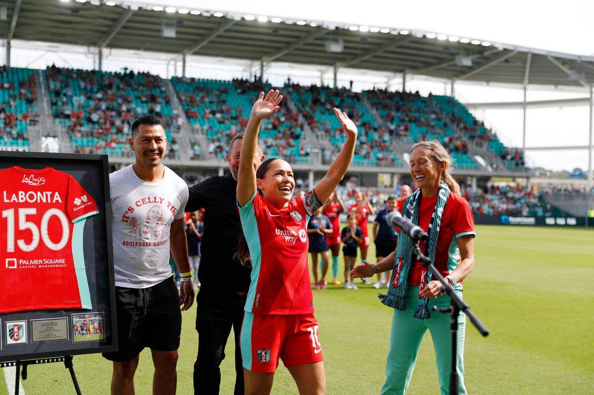 Kansas City Current star Lo LaBonta, center, was honored before Saturday’s match against NJ/NY Gotham FC at CPKC Stadium. Behind her to the left is former Sporting KC midfielder Roger Espinoza, her husband who now coaches with the Current’s MLS neighbor in KC.