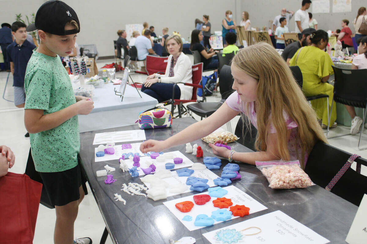 Micah Beck, 10, learns about 3-D printed fidget toys from Anna Beth Burns, 10, of Overland Park, during the KidsFest Business Fair in Shawnee Sept. 9.