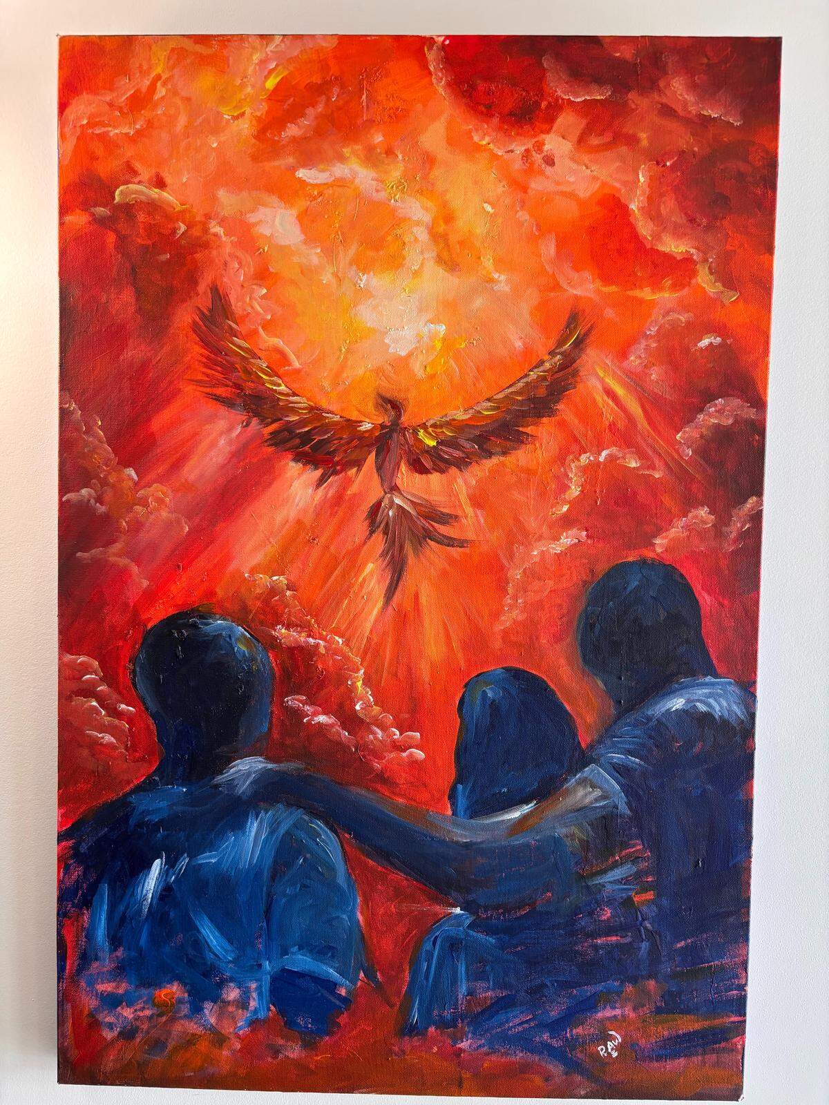 A painting by Remy Wharry hangs inside Raw Art Studio, depicting three figures looking toward a bird rising through a bright red and orange sky.