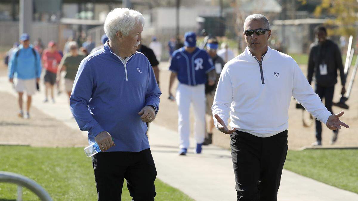 Kansas City Royals owner John Sherman, left, and general manager Dayton Moore walk between practice fields during spring training baseball practice Monday, Feb. 17, 2020, in Surprise, Ariz. (AP Photo/Charlie Riedel)