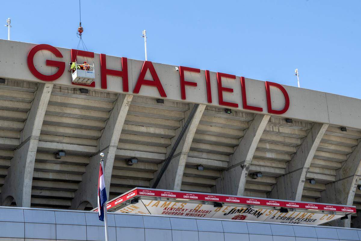 Workers are seen suspended near the GEHA Field sign at Arrowhead Stadium on Monday, May 11, 2026. Crews are preparing the stadium for the FIFA World Cup.