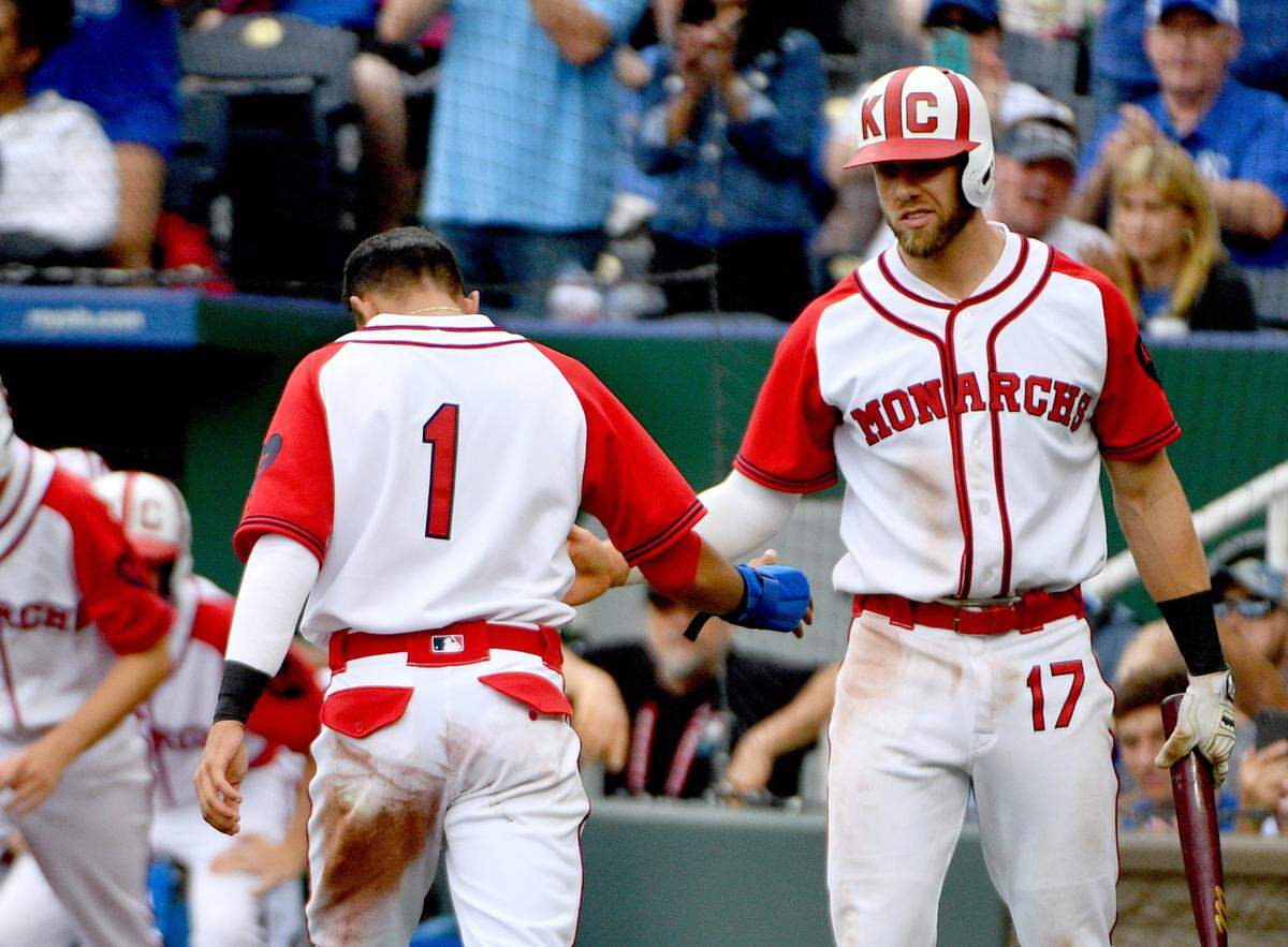 Kansas City Royals second baseman Nicky Lopez (1) is congratulated by third baseman Hunter Dozier (17) after scoring in the seventh inning against the Minnesota Twins at Kauffman Stadium on June 23, 2019. The Royals wore KC Monarchs jerseys for the game.
