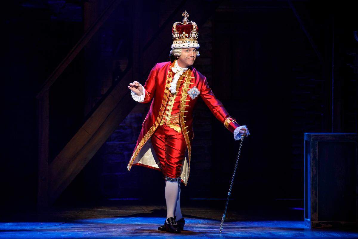 In “Hamilton,” England’s King George III (Jon Patrick Walker) is none too happy with the troublesome colonists.
