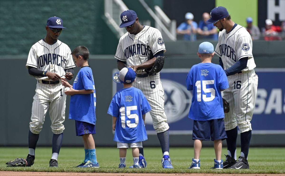 Wearing Negro League Monarch uniforms, (from left) Kansas City Royals’ Jarrod Dyson (1), Lorenzo Cain (6) and Paulo Orlando (16) sign autographs before the start of a baseball game against the New York Yankees on May 17, 2015 at Kauffman Stadium in Kansas City, Mo.
