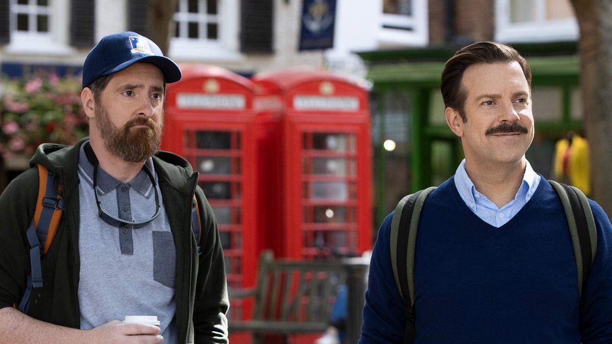 Ted Lasso (Jason Sudeikis, right) has an assistant coach (Brendan Hunt) who is usually in a hat, often one with a Kansas City reference.
