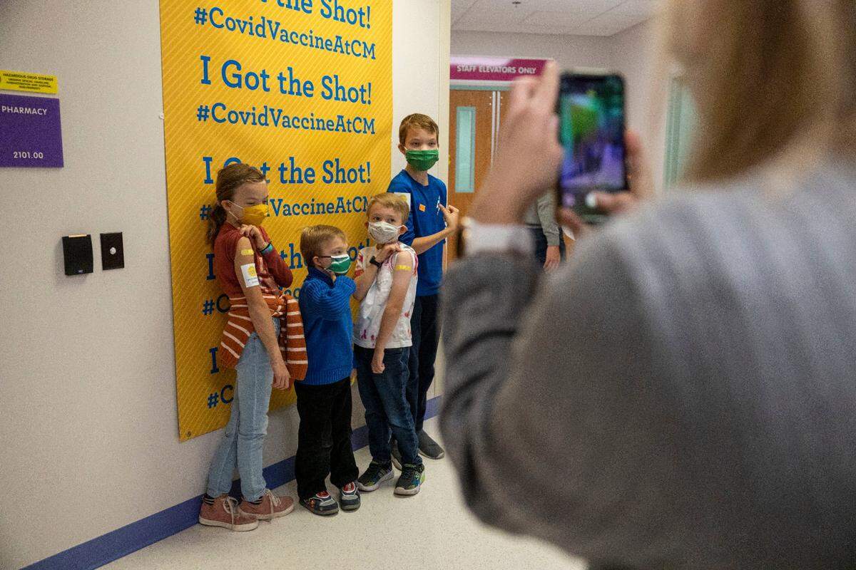 Sarah Edwards takes a photo of her children after they receive their first COVID-19 vaccine dose at Children’s Mercy Hospital Kansas in Overland Park.