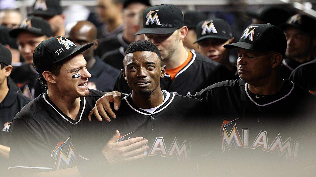 Derek Dietrich (left) consoled Marlins teammate Dee Gordon (center) after Gordon led off Monday night's game against the New York Mets with a home run. The teams had just finished paying tribute to Marlins pitcher Jose Fernandez, who was killed in a boating accident early Sunday.