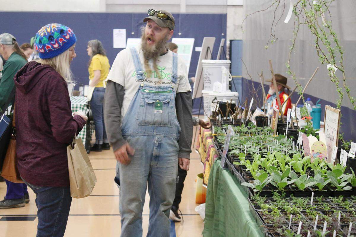 Cindy Meeder of Shawnee learns about the various plants on offer from Antioch Urban Growers as she chats with Mac McAdams at the Eat Local & Organic Expo at Johnson County Community College.