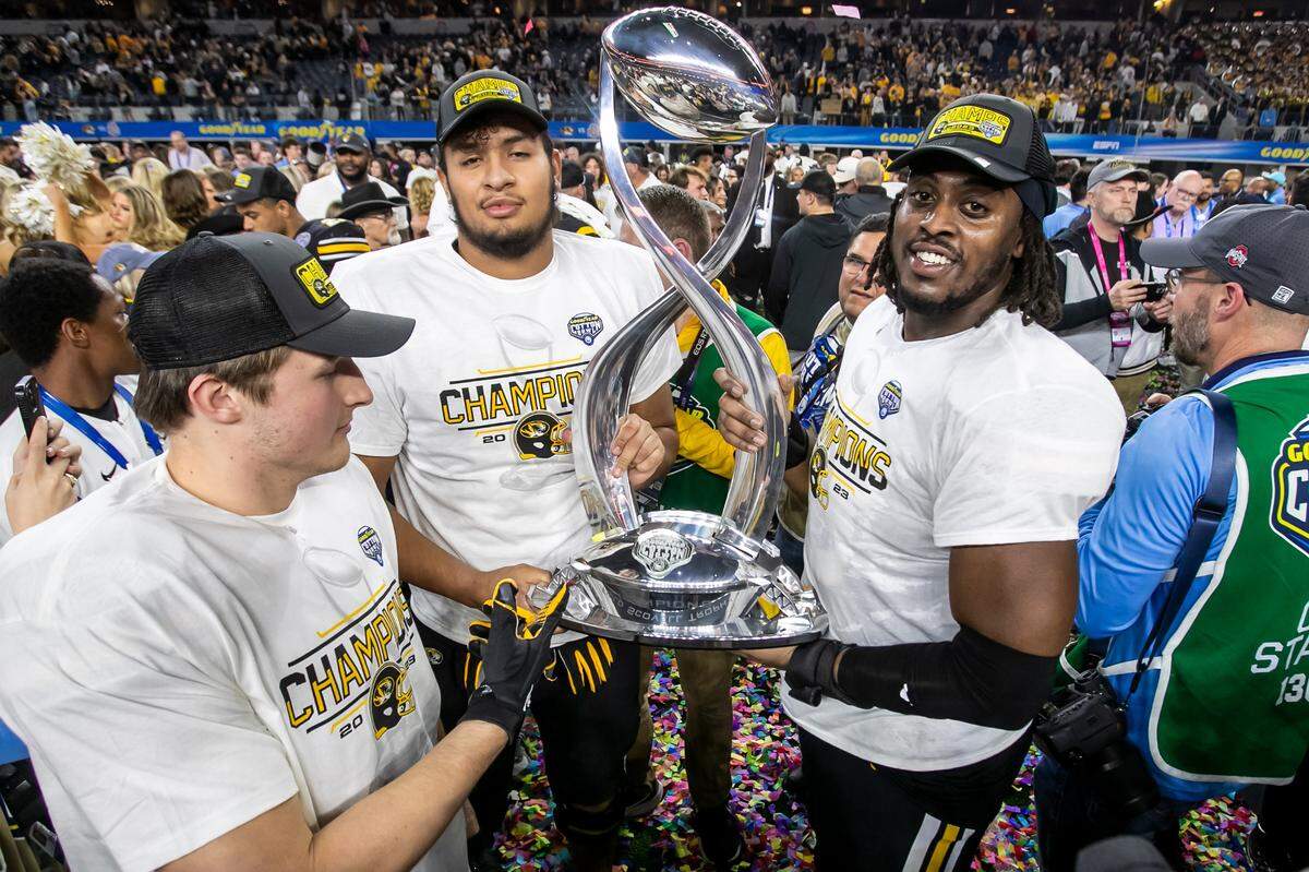 Members of the Missouri Tigers football team pose with the Cotton Bowl trophy after Friday’s 14-3 win against Ohio State at AT&T Stadium in Arlington, Texas.