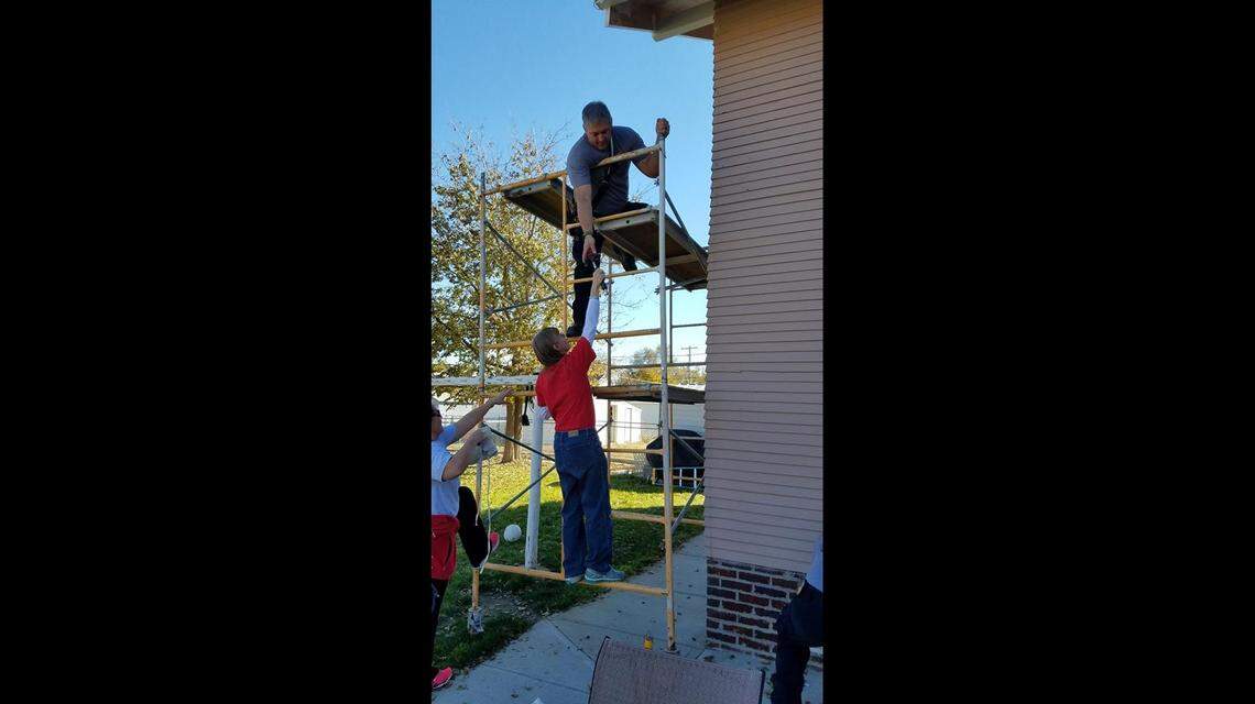 Volunteers from the McCook Fire Department string lights on the home of their late colleague, Raleigh Haas.