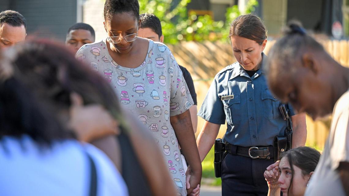 Kansas City Police Chief Stacey Graves held hands with Cherron Barney, left, and another woman as people gathered in the street to pray after three people died and five were injured following a shooting early Sunday, June 25, 2023, near 57th Street and Prospect Avenue in Kansas City.