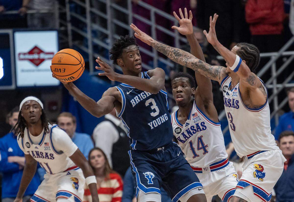 BYU Cougars forward AJ Dybantsa (3) was defended by Kansas Jayhawks guards Melvin Council Jr. (14), Tre White (3) and Jamari McDowell (11) in the first half at Allen Fieldhouse on Saturday, Jan. 31, 2026, in Lawrence.