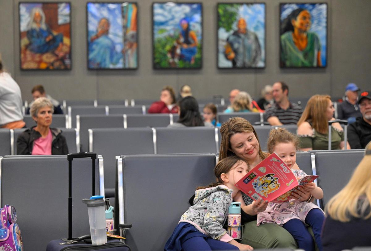 Jessica Woolery of Olathe read to her daughters Brooklyn, 7, and Hayden, 4, right, at the new $1.5 billion single terminal at Kansas City International Airport on Tuesday, Feb. 28, 2023. “It was so easy,” said Jessica Woolery. “It’s beautiful, amazing.” Woolery and her husband Chris Woolery were taking the girls to Orlando.