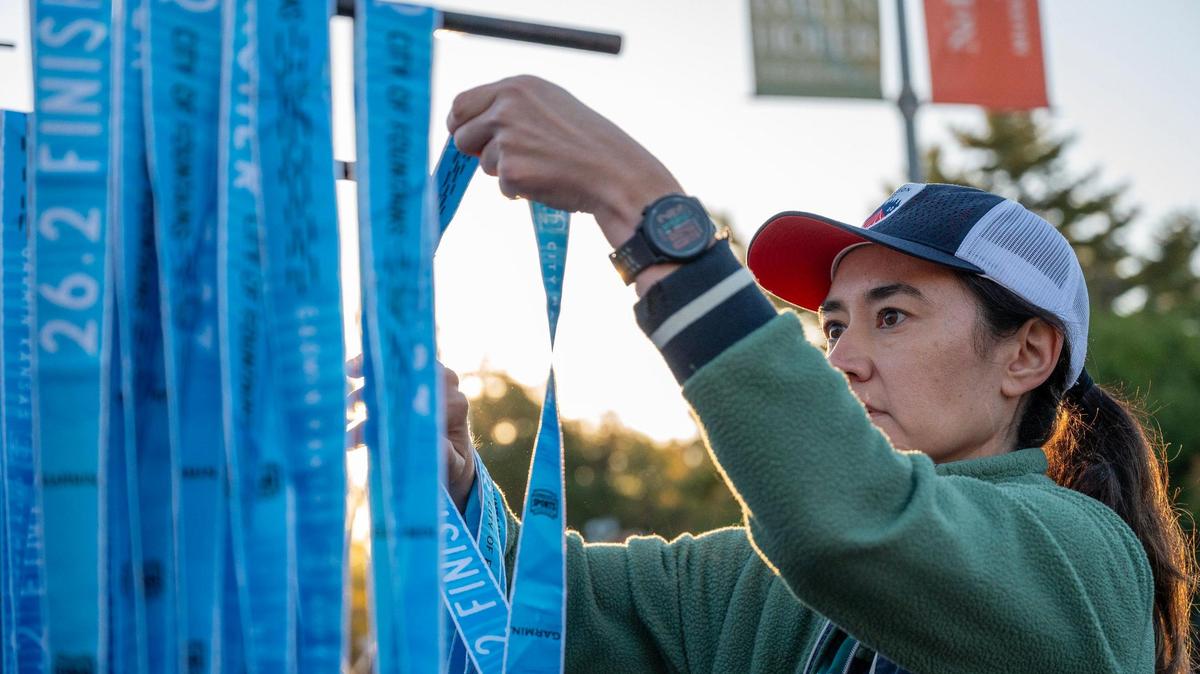Volunteer Ashley Ross arranges medals on a rack for distribution to runners upon completion of Saturday’s 2023 Garmin Kansas City Marathon.