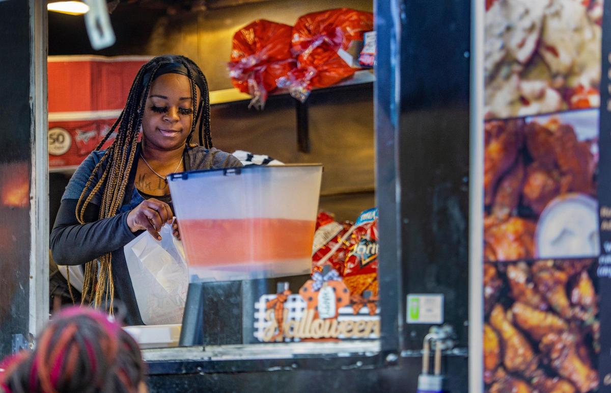 Kay Clark, owner of KC’s Wing Bar food truck, fills an order for a customer at a Halloween event in the 18th & Vine District.