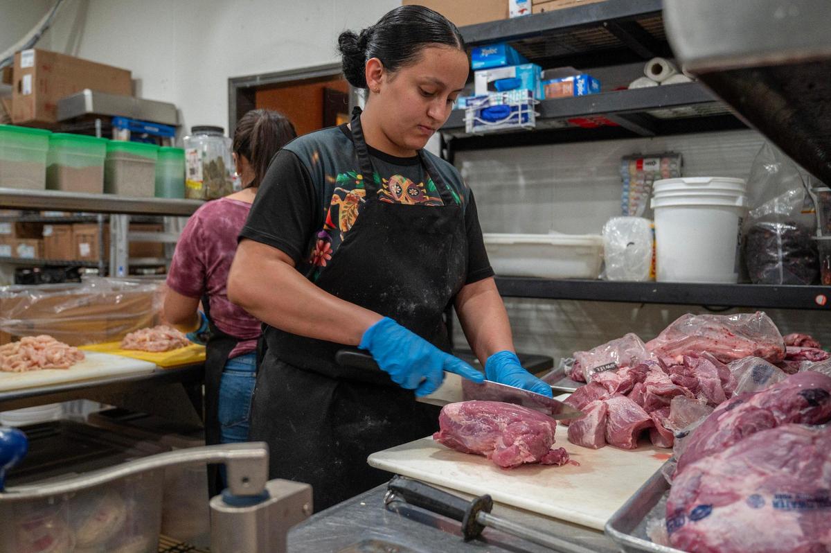 Christina Pinto, a food preparer at Dos Reales Mexican restaurant, cuts pieces of pork to make carnitas. Making the “little meats” takes about five hours.