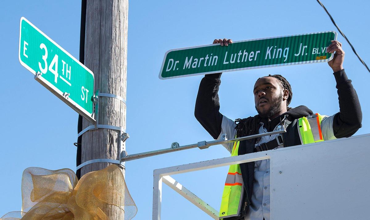 DeAnthony Jackson handled the ceremonial installation of the first new Dr. Martin Luther King Jr. Boulevard street sign on Monday at 34th Street and The Paseo in Kansas City. The Paseo was renamed to honor King.