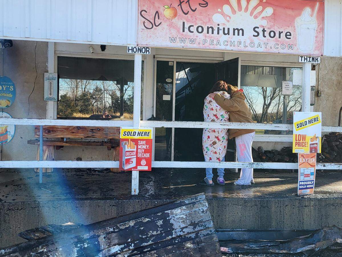 People stand outside Scott’s Iconium General Store comforting each other after fire gutted the store on Sunday, Dec. 22.