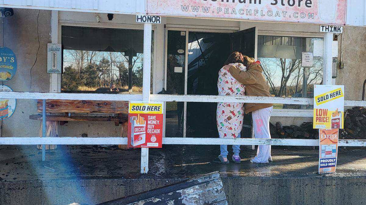 People stand outside Scott’s Iconium General Store comforting each other after fire gutted the store on Sunday, Dec. 22.