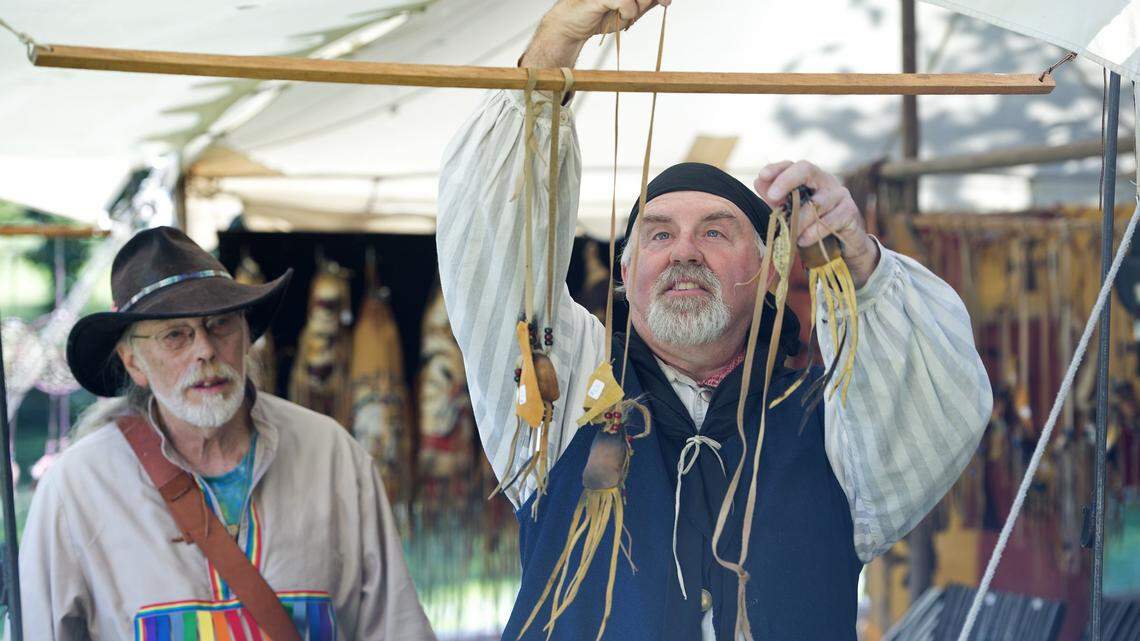 Lee Slusher (left) of Merriam, looked on as Chuck Lanphear of Independence, Mo., a member of the Missouri Free Trappers, added lmore leather medicine bags to a display at his trader's tent during the Fall Festival held Sunday, Oct. 11, 2015, at the Shawnee Indian Mission State Historic Site in Fairway.