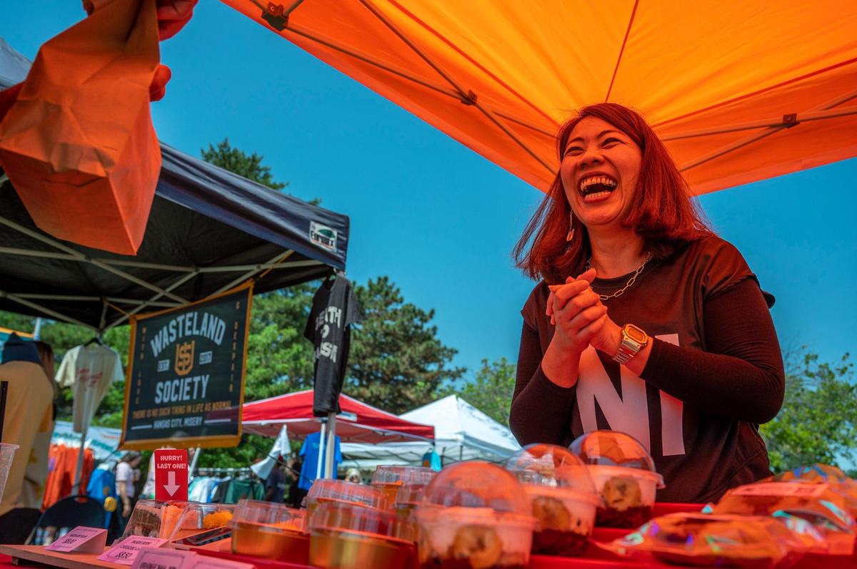 Yuei Costello helps a customer purchase a baked good at the Mooyuei Baker booth during the AAPIconic Festival on Saturday, May 20, 2023, in Kansas City.