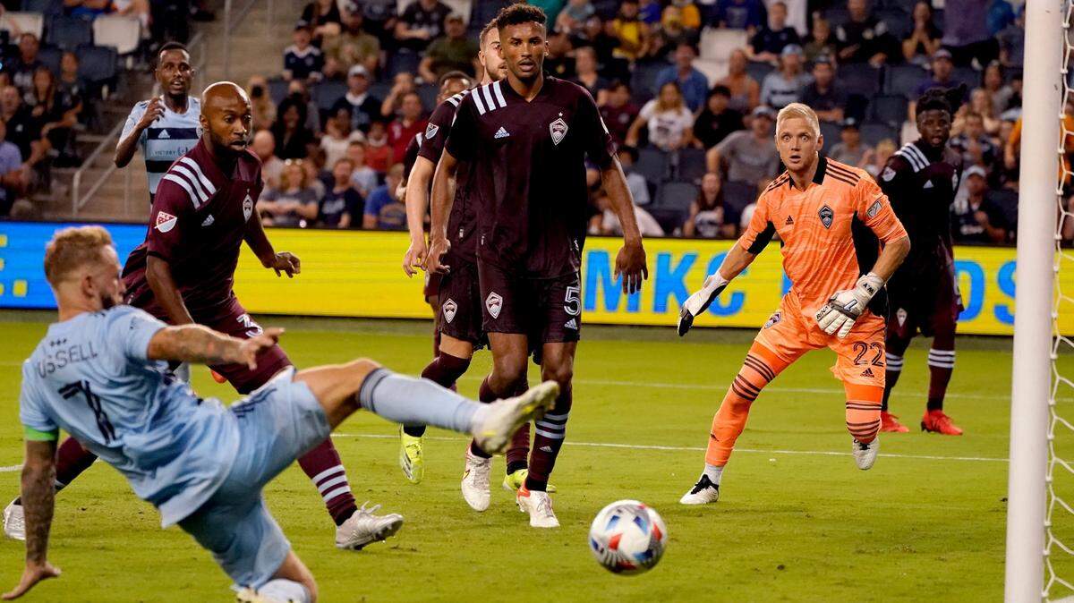 Sporting Kansas City forward Johnny Russell (7) takes a shot that was blocked by Colorado Rapids defender Auston Trusty (5) during the second half of an MLS soccer match Saturday, Aug. 28, 2021, in Kansas City, Kan. (AP Photo/Charlie Riedel)
