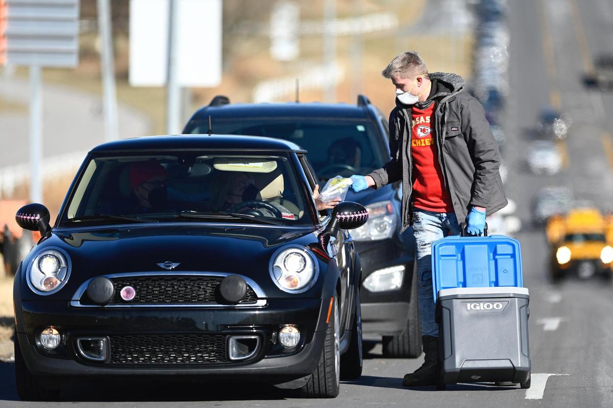 AIM Laboratories Volunteer Bobby Sheehan hands out COVID-19 test kits to people in cars lined up along Blue Ridge Boulevard during a mass testing clinic that opened Monday, January 10, 2022, in the parking lot of Kauffman Stadium in Kansas City. AIM Laboratories in Bridgetown, Missouri,. hoped to conduct 1,650 self-swab tests each day of testing at Kauffman. The testing will go on through Tuesday and Wednesday for people who have pre-registered for the test.