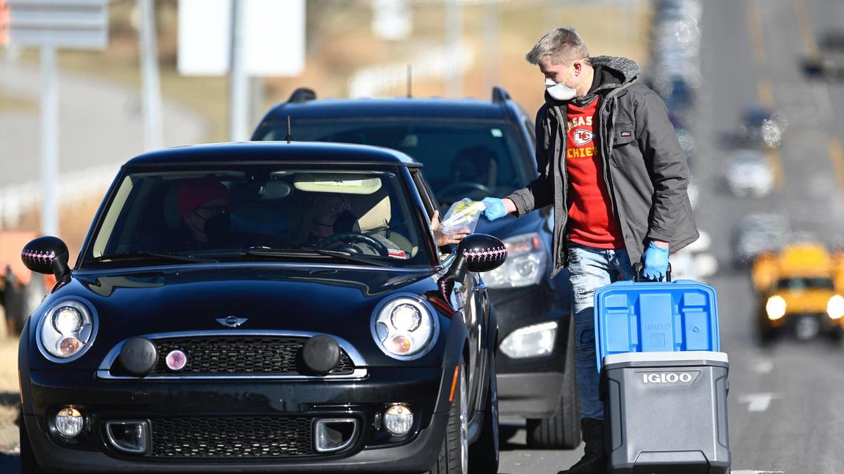 AIM Laboratories Volunteer Bobby Sheehan hands out COVID-19 test kits to people in cars lined up along Blue Ridge Boulevard during a mass testing clinic that opened Monday, January 10, 2022, in the parking lot of Kauffman Stadium in Kansas City. AIM Laboratories in Bridgetown, Missouri,. hoped to conduct 1,650 self-swab tests each day of testing at Kauffman. The testing will go on through Tuesday and Wednesday for people who have pre-registered for the test.