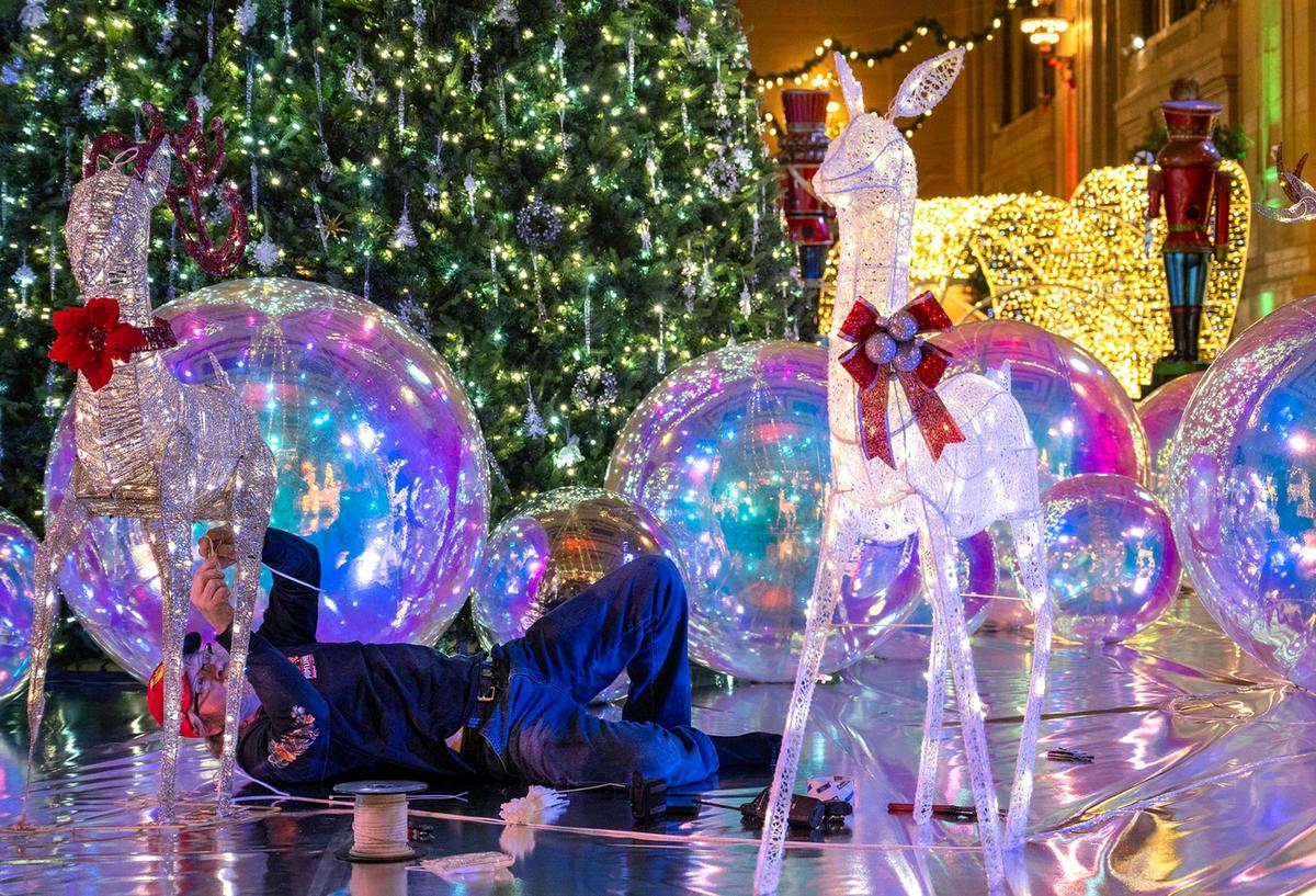 Steve Uhlir of Cleveland, Ohio, works on the reindeer in the display around a 30-foot tall Christmas tree Wednesday at the Holiday Reflections display in Union Station’s Grand Plaza.